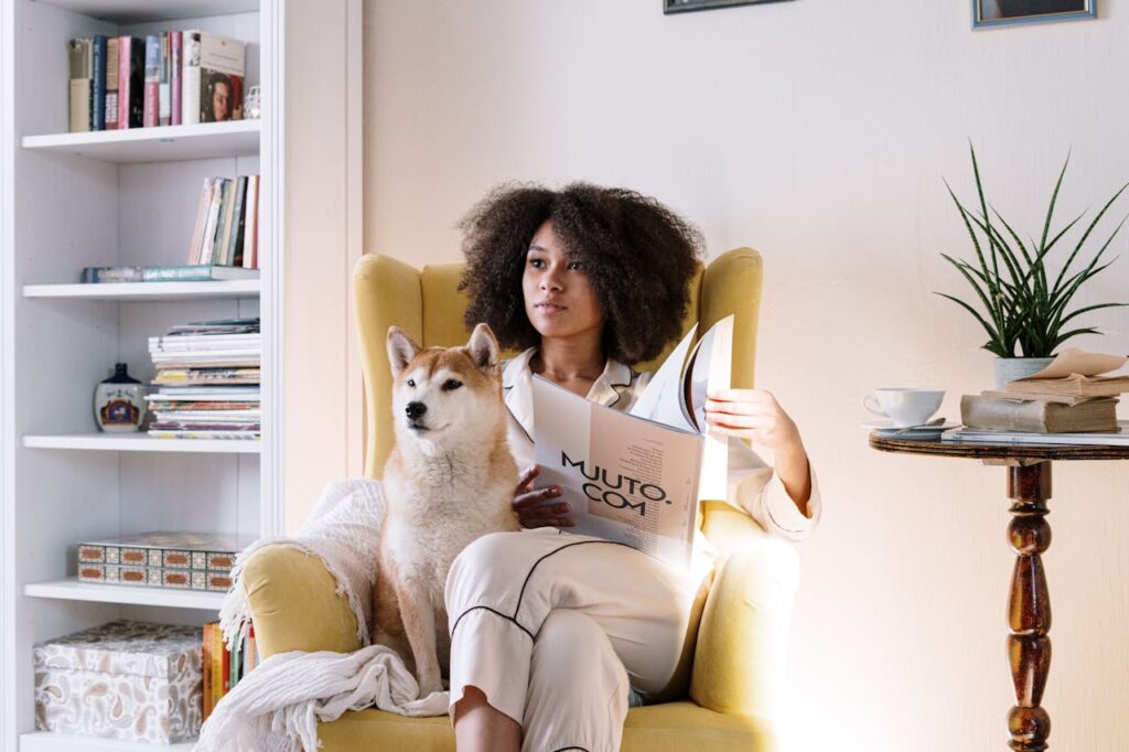 Donna con capelli ricci afro legge rivista seduta su poltrona