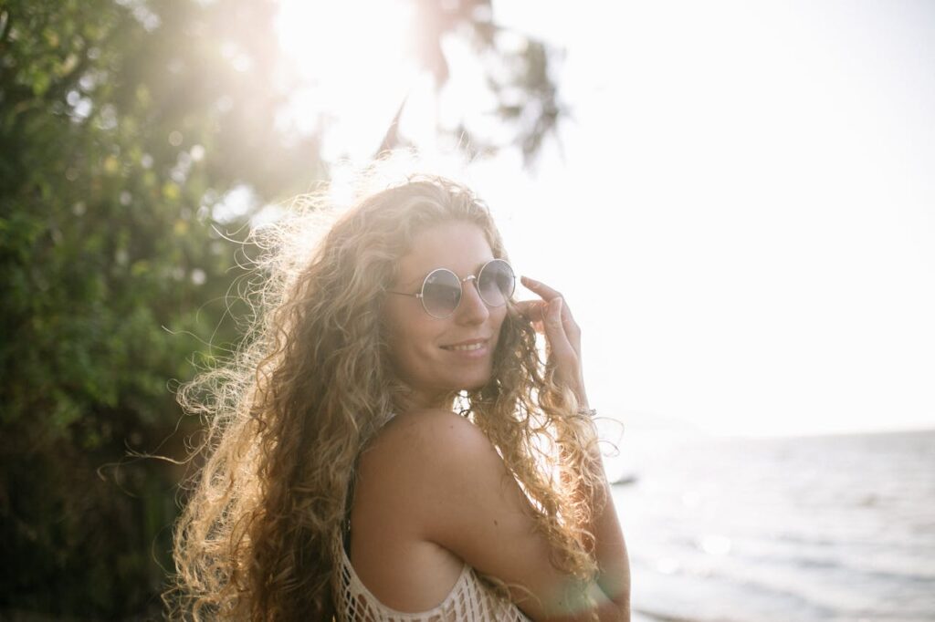 Donna con capelli lunghi ricci e occhiali da sole