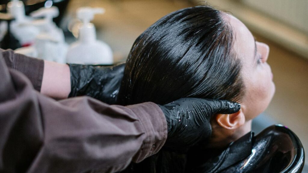 Parrucchiere lava capelli neri di una donna in lavatesta