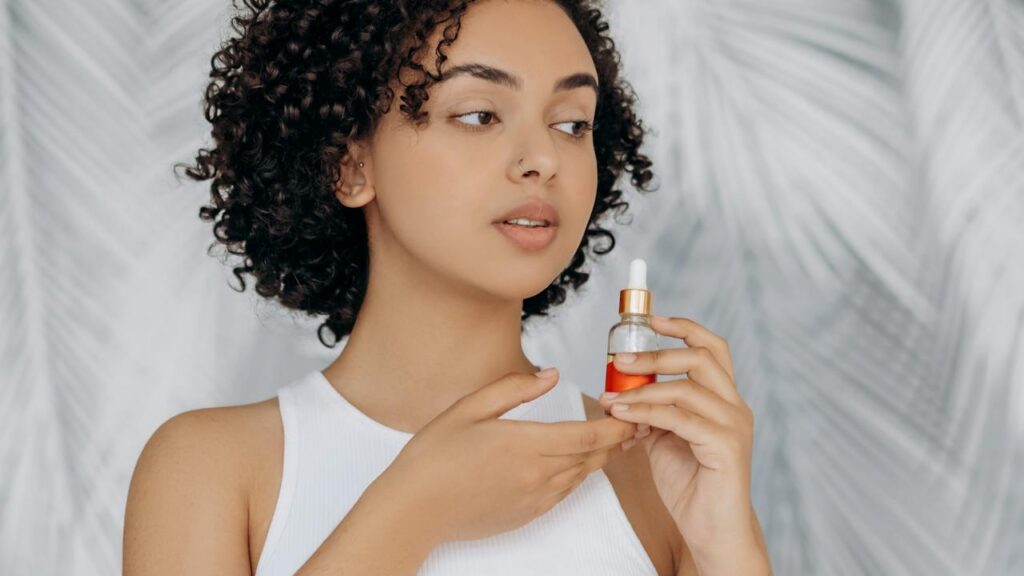 Donna con capelli ricci neri e flacone per la cura dei capelli